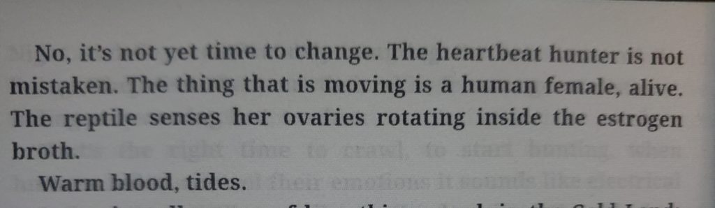 A screen shot of an eReader with text that reads "No, it's not yet time to change. The heartbeat hunter is not mistaken. The thing that is moving is a human female, alive. The reptile senses her ovaries rotating inside the estrogen broth. Warm blood, tides."