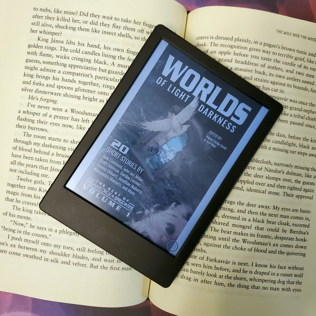 An image of an eReader displaying the Worlds of Light and Darkness anthology cover.