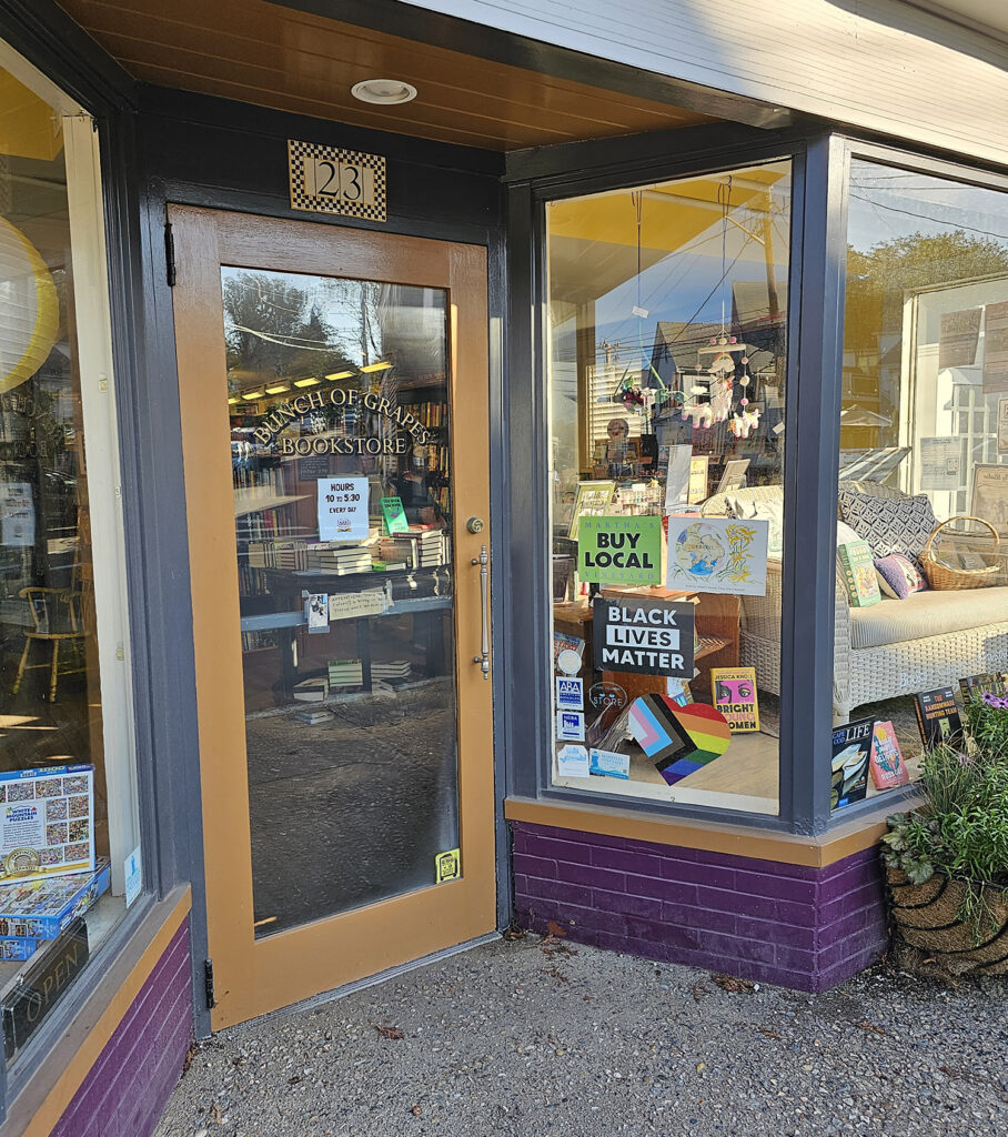 The storefront for Bunch of Grape Books. There is a pride flag and "Buy Local" and "Black Lives Matter" signs in the window.