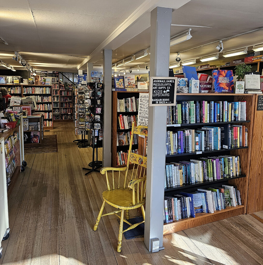 An interior shot of Bunch of Grapes. There is a rocking chair front and center. The shelves are brown and black.