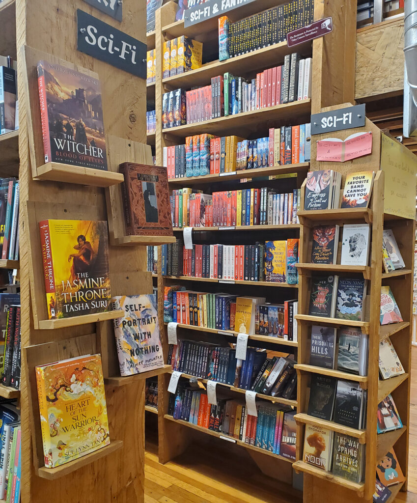 The sci-fi section at Elliott Bay Books. The shelves are unfinished wood.