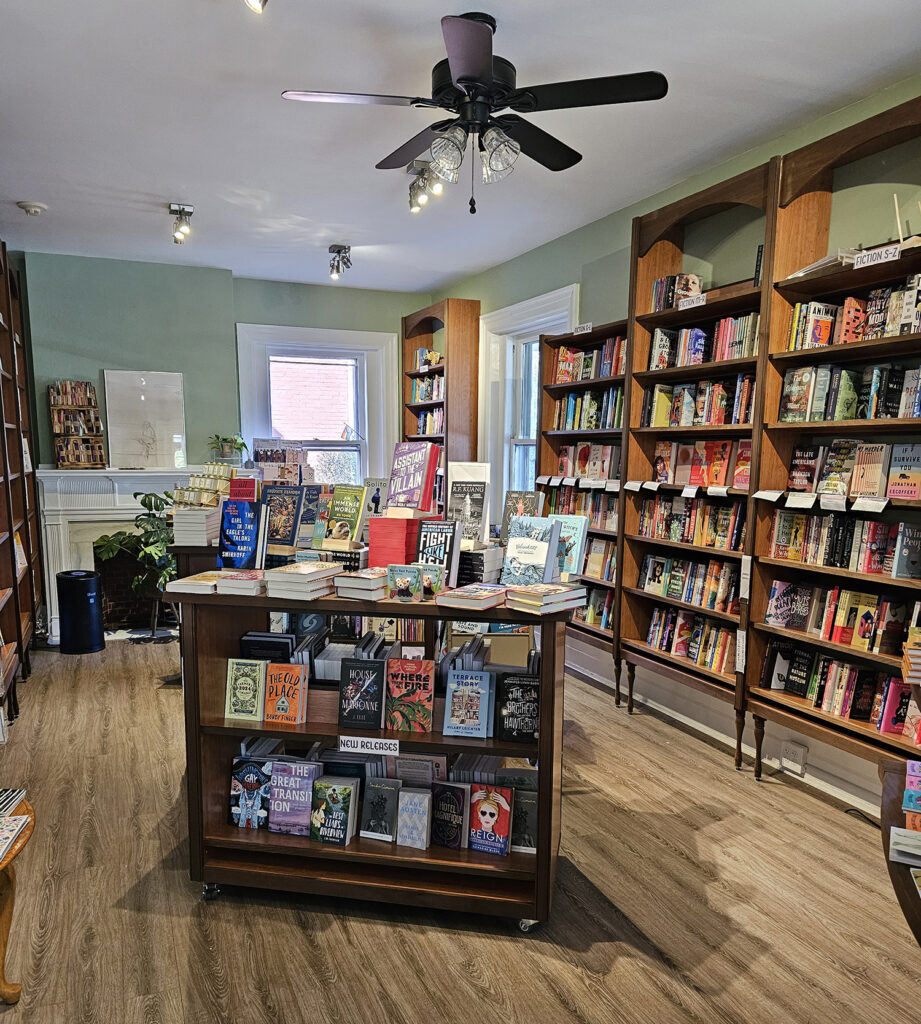 The interior of Pocket Books. The walls are mint green and the shelves are a deep brown wood with arched faces at the top.