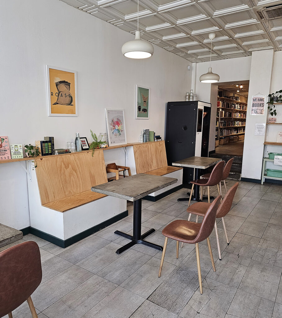 The interior of Pressed Coffee and Books showing booths and tables, with a peek into the backroom where the books are located.
