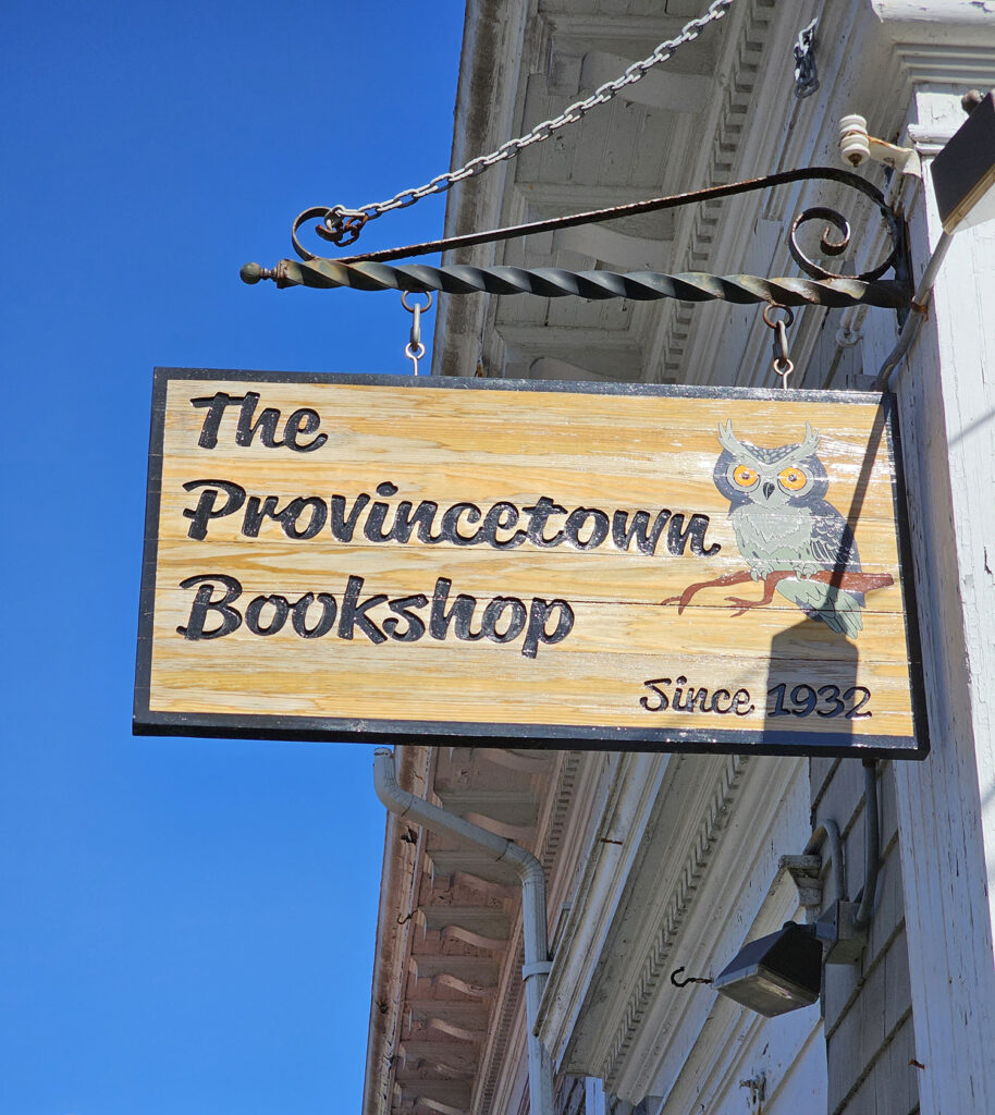 The sign for Provincetown Bookshop. It is wooden with a gray owl painted on it.